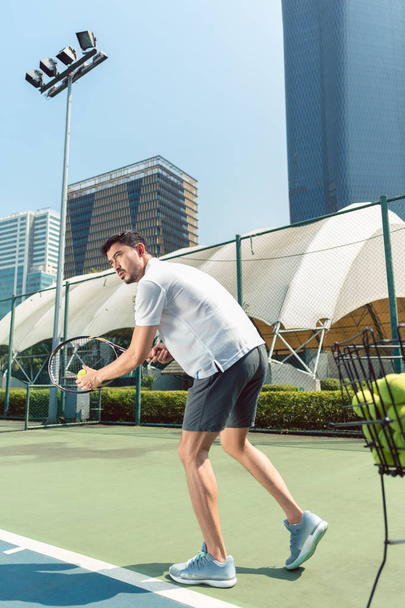 A fiatalember játék tenisz, szabadban, egy modern kerületben, a város - Fotó, kép