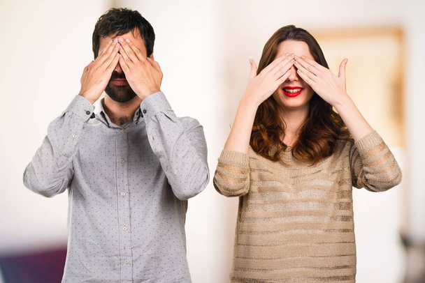 Young couple covering their eyes on unfocused background - Φωτογραφία, εικόνα