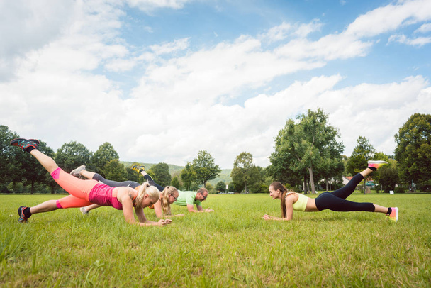 Familie planking buiten in weiland met fitness leraar - Foto, afbeelding
