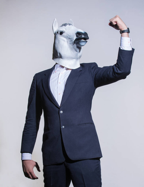 Ein Mann in Anzug und Pferdemaske auf hellem Hintergrund. konzeptioneller geschäftlicher Hintergrund - Foto, Bild