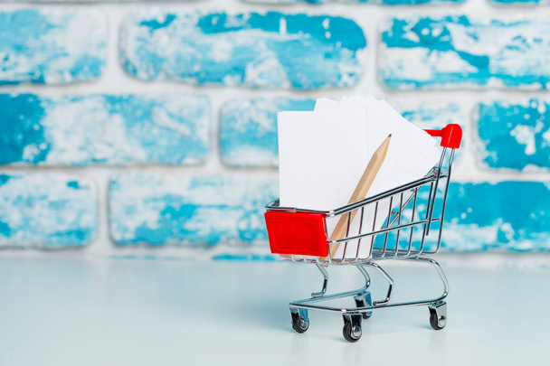 Stationery items in shopping trolley at left side - Foto, afbeelding