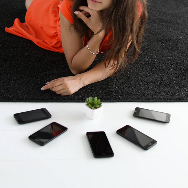 5 telefonları ve etli bitki ile turuncu elbiseli bir kız, yakın çekim - Fotoğraf, Görsel
