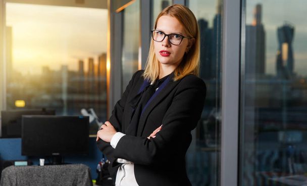 Photo of woman with glasses with arms crossed by glass wall in - Foto, imagen