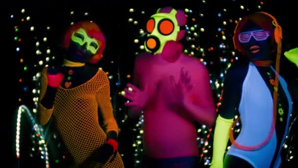 Sexy women and guy in gas mask in fluorescent clothing under UV black light - Footage, Video