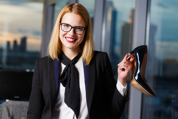 Photo of smiling woman with glasses with shoe in hands - Foto, imagen