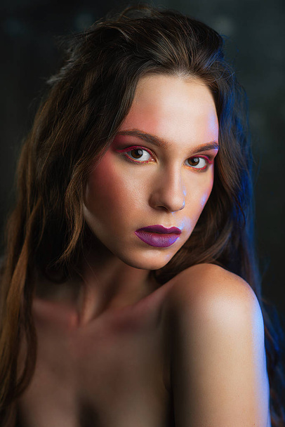 Beauty Women Face. Beautiful young model with bright face makeup. Portrait of sexy girl with purple lips - Zdjęcie, obraz
