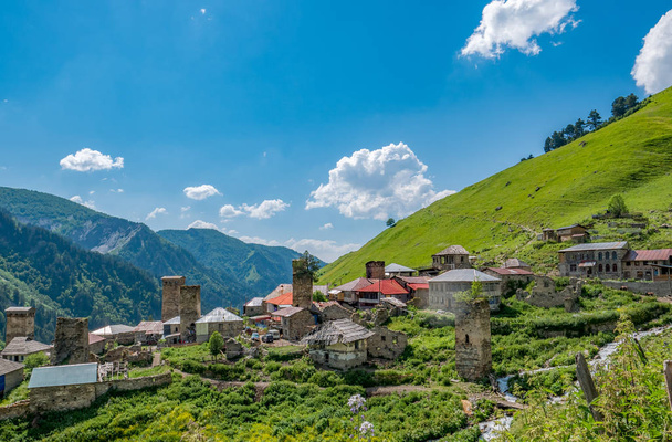 Wonderful view on village in the mountains against blue sky in Svaneti region, Georgia. Traditional ancient Svan Towers on a green hill in a sunny day - Photo, Image