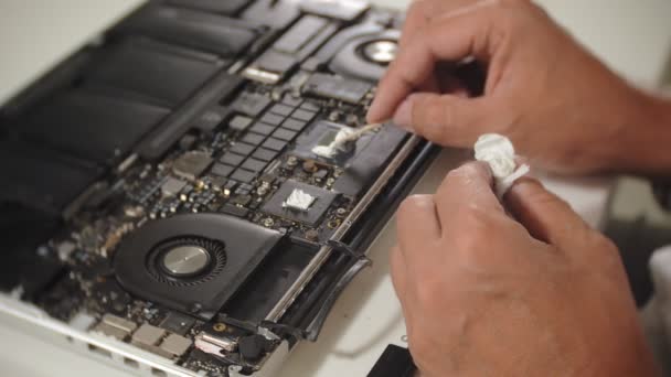 Een man repareert een laptop. Het concept van computer reparatie. Close-up van de mens reparatie laptop moederbord met een schroevendraaier. Onderhoud van de hardware van het moederbord. Schijfhouder, computer reparatie - Video