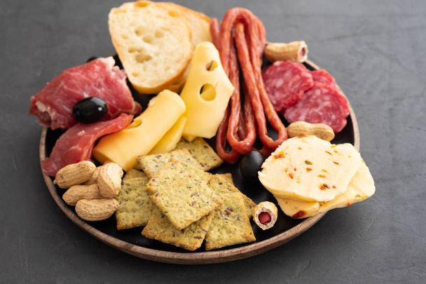 Meat and cheese plate.Traditional italian antipasto, cutting board with salami, cold smoked meat, prosciutto, ham, cheeses, olives, capers on black background. Cheese and meat appetizer. Top view. - Fotoğraf, Görsel