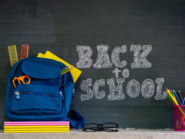 Back to school concept. School bag with stationery and notebooks in front of blackboard. - Photo, Image