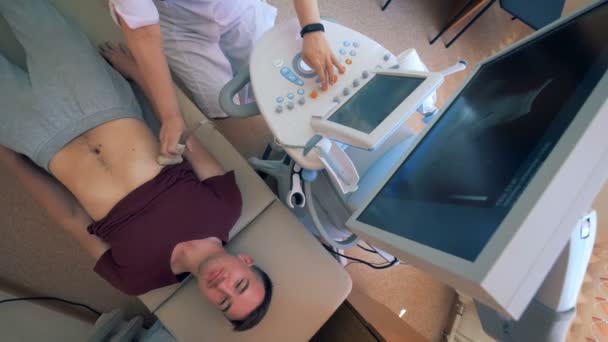 Male patient is getting his abdomen scanned by ultrasound machine - Video, Çekim