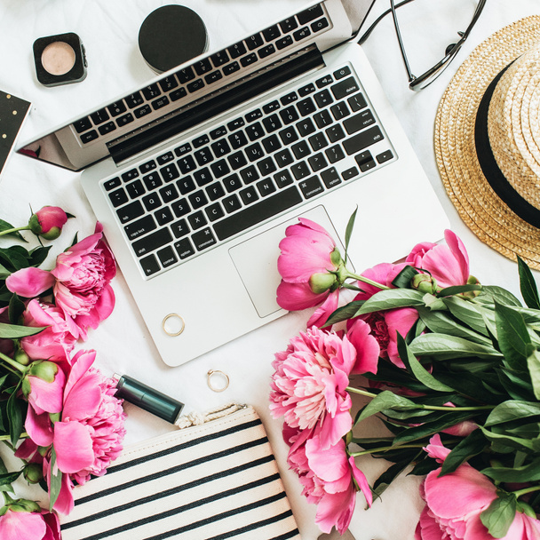 Επίπεδη lay μόδα θηλυκή γραφείο με το lap-top, ροζ παιωνία λουλούδια, καλλυντικά, αξεσουάρ. Το Top view νεκρή blogger φόντο. - Φωτογραφία, εικόνα