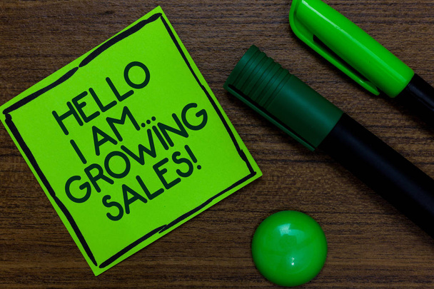 Text sign showing Hello I Am... Growing Sales. Conceptual photo Making more money Selling larger quantities Written on sticky note two markers laid on wooden floor green ball - Photo, Image