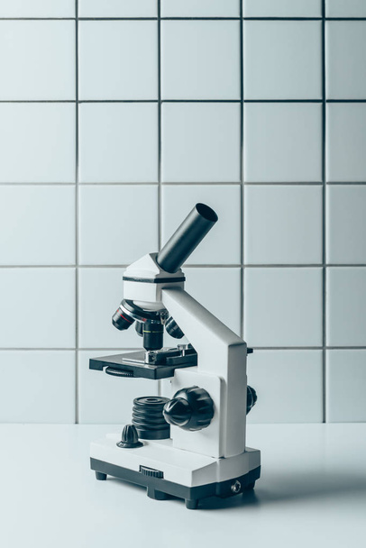 optical microscope on white tablet in front of tiled wall - Foto, afbeelding