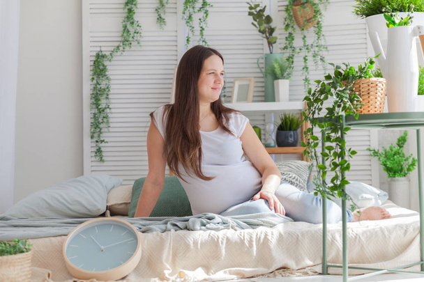 Young pregnant woman posing in light modern scandinavian bedroom interior - Foto, immagini
