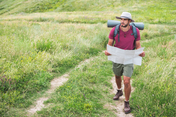 hiker in hat with backpack holding map and walking on path - 写真・画像