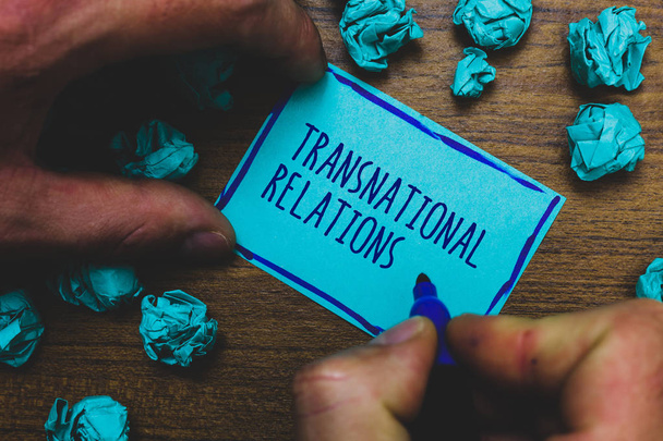 Writing note showing Transnational Relations. Business photo showcasing International Global Politics Relationship Diplomacy Foggy hand hold marker drawn blue notepad paper lump on wooden floor - Photo, Image
