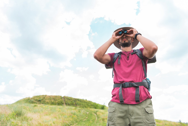 male traveler in hat with backpack looking in binoculars - Photo, Image