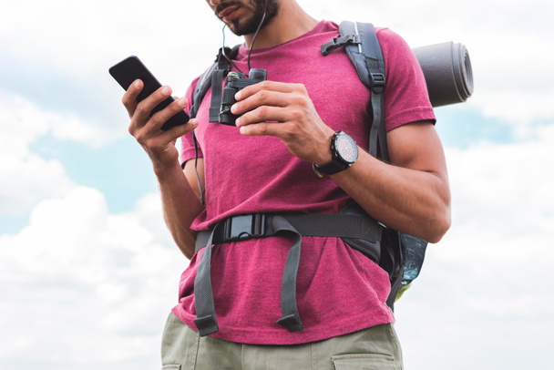 sırt çantası ve smartphone kullanarak dürbün ile turist görünümünü kırpılmış  - Fotoğraf, Görsel