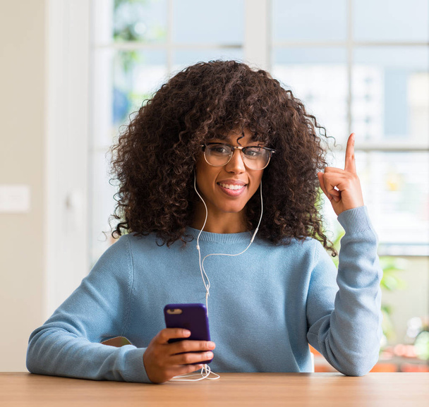 Bir fikir ya da soru işaret parmağı gülen yüz, bir numara ile Smartphone sürpriz kullanan güzel Afrikalı-Amerikalı kadın - Fotoğraf, Görsel