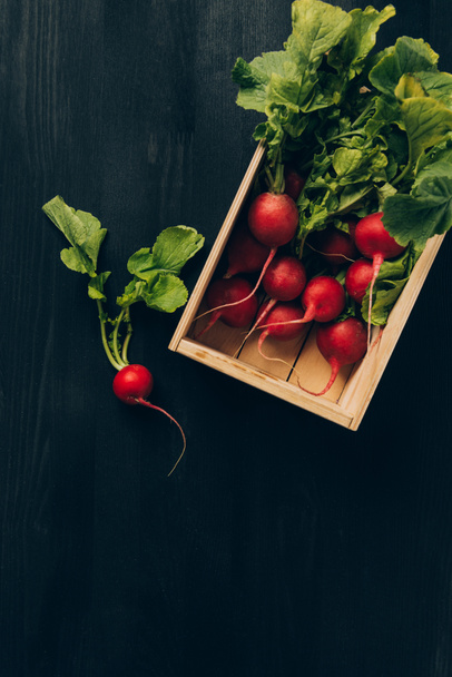 elevated view of radishes in wooden box on grey dark table - Foto, Imagem