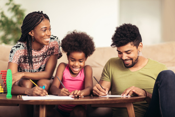 Mom and dad drawing with their daughter. African american family spending time together at home. - Фото, изображение