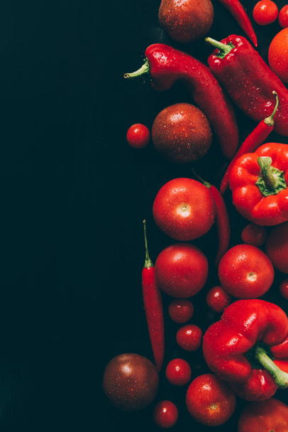 top view of red tomatoes, bell peppers and chili peppers on grey dark table - 写真・画像