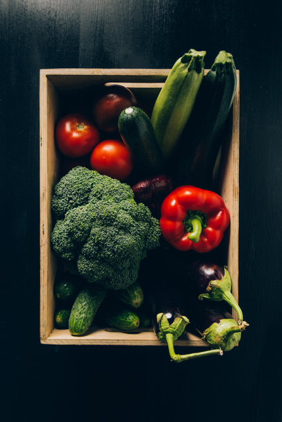 top view of zucchini, broccoli and eggplants in wooden box on dark table - Fotoğraf, Görsel