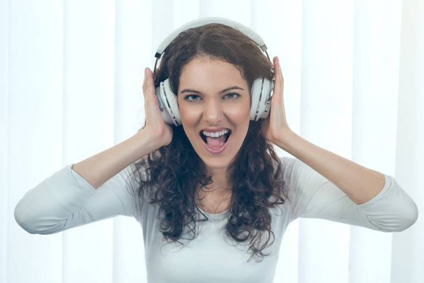 Emotional portrait of teen girl listening aggressive music in headphones - Foto, Bild