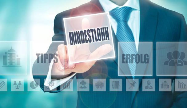 ドイツ語で未来的なコンピューターのディスプレイのボタンでは最低賃金"Mindestlohn"を押すと実業家 - 写真・画像