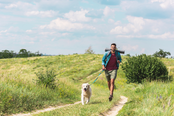 traveler running with dog on path on summer meadow - Fotoğraf, Görsel