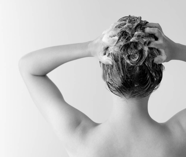 Woman shampooing her hair from the back in black and white - 写真・画像