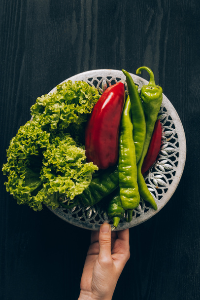 cropped image of woman holding plate with green salad and chili peppers - Фото, зображення