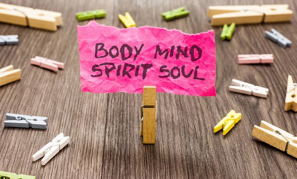 Conceptual hand writing showing Body Mind Spirit Soul. Business photo showcasing Personal Balance Therapy Conciousness state of mind Paperclip hold pink note with texts many clips wooden floor - Photo, Image
