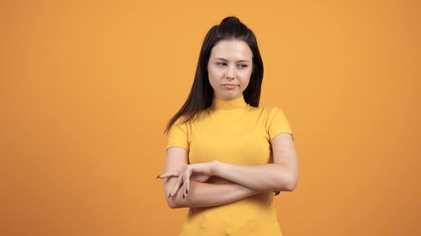 Unhappy woman on vivid orange background - Materiał filmowy, wideo
