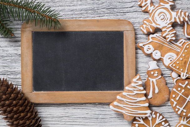 クリスマス装飾。モミの木小枝、ジンジャーブレッド クッキーと黒板。本文の空白. - 写真・画像