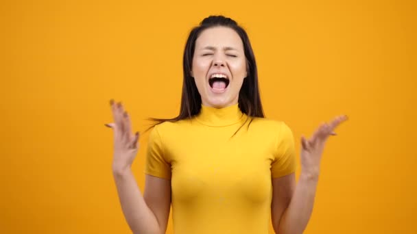 schöne verrückte Frau schreit im Studio über lebendige orange Hintergrund - Filmmaterial, Video