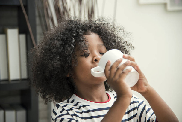 かわいいアフリカ系アメリカ人の少年は、マグカップと医療の概念と人の生活から水を飲む. - 写真・画像