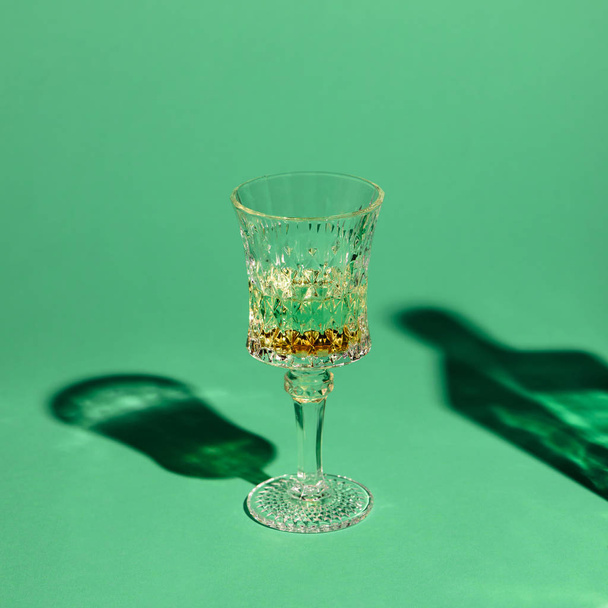 close-up shot of crystal glass of absinthe on green surface - Фото, изображение