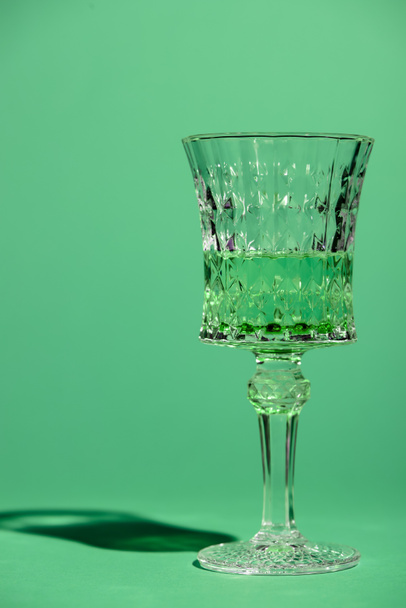 primer plano de cristal de absenta aislado en verde
 - Foto, Imagen