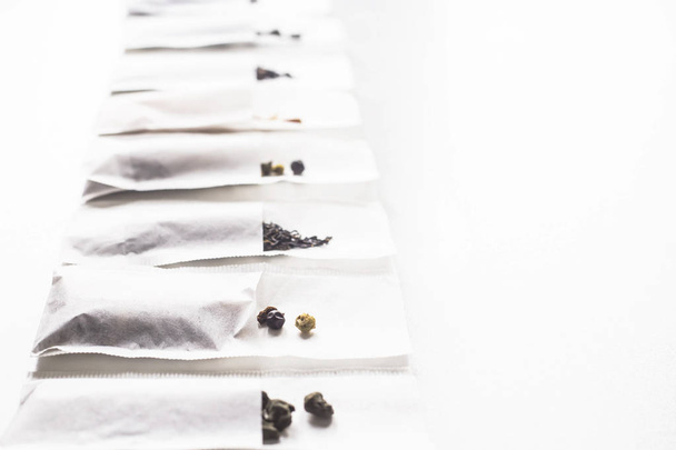 Different kinds of tea in disposable filter packs lined up in a row on a white background - Fotó, kép