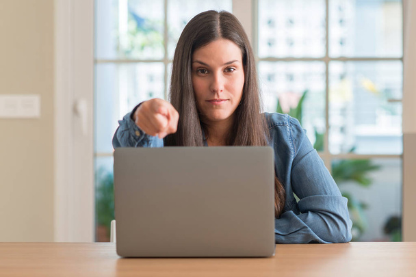 Молода жінка використовує ноутбук вдома, вказуючи пальцем на камеру і до вас, знак руки, позитивний і впевнений жест спереду
 - Фото, зображення