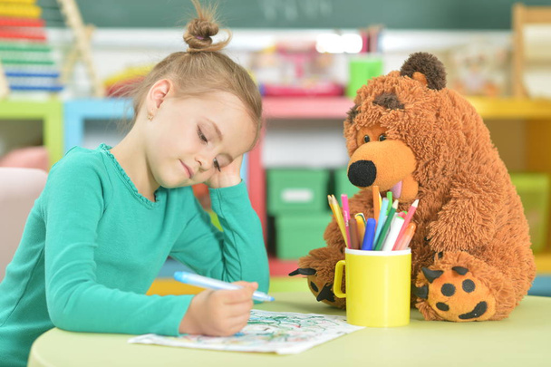  cute little girl drawing with felt pen while sitting at table in her room - Photo, image