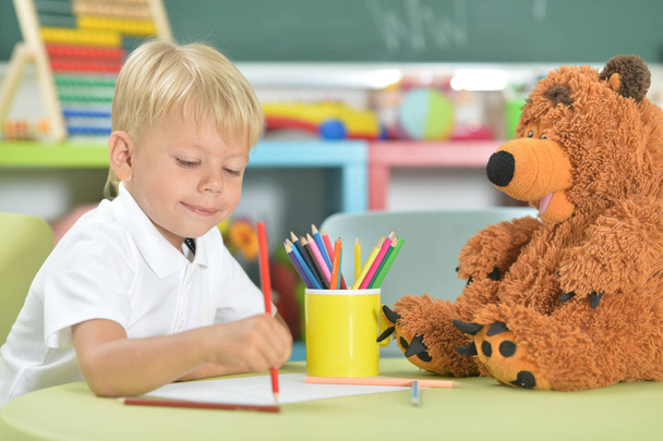 Portrait of cute little boy drawing with pencils in classroom - Foto, Imagem