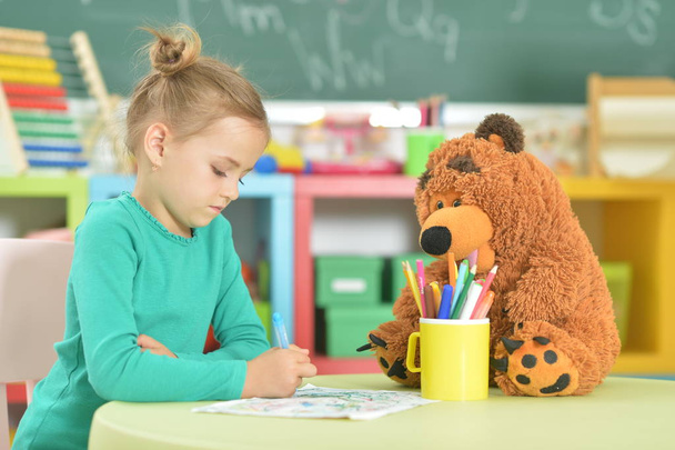  cute little girl drawing with felt pen while sitting at table in her room - Фото, зображення