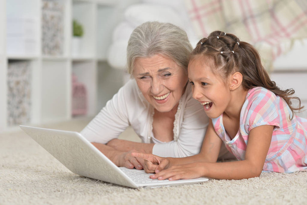  little girl with her grandmother  using  laptop  - Фото, изображение