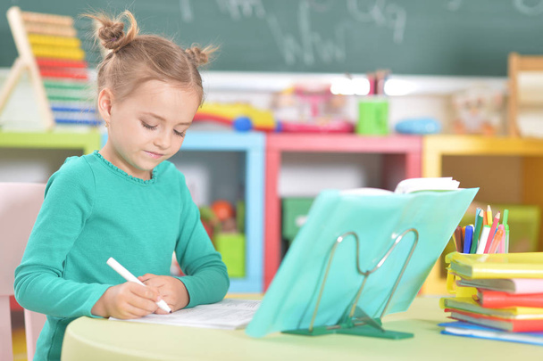 Милая счастливая школьница делает домашнее задание
 - Фото, изображение