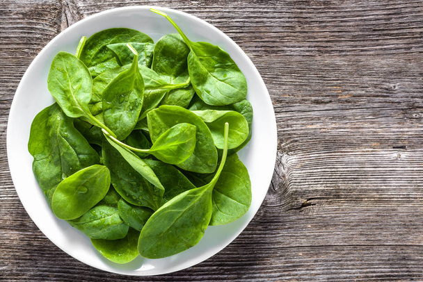 Fresh spinach. Green vegetable leaves on plate, healthy food, vegan diet concept. - Foto, Imagem