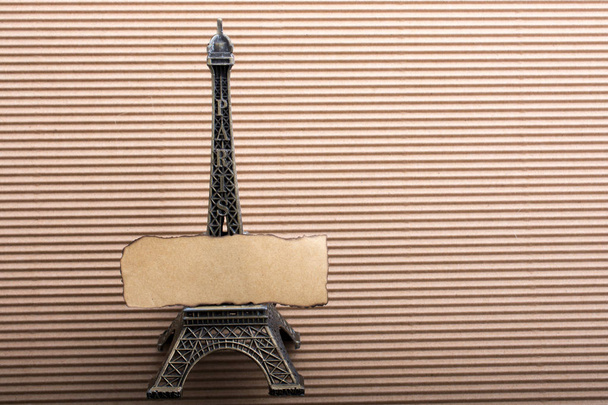 Burnt piece of paper on model Eiffel tower on cardboard - Photo, Image