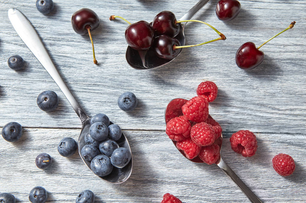 Sweet berries pattern from organic ripe fresh blueberries, cherries and raspberries on gray background. Healthy clean eating. Flat lay - Foto, immagini